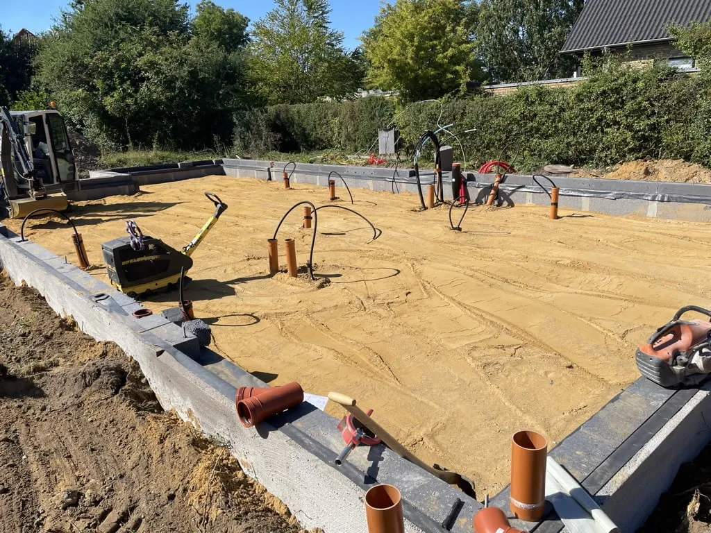 Byggeplads med fundament og rørinstallationer